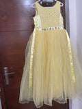 Yellow dress with floral details on a hanger against a wooden door background