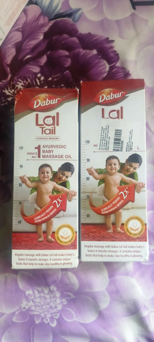 Two boxes of Dabur Laitail massage oil for babies on a floral background