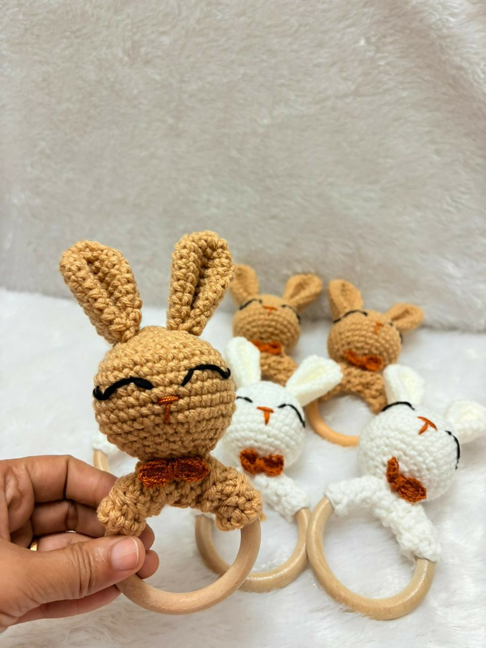 Set of crochet bunny toys with wooden rings on a textured surface