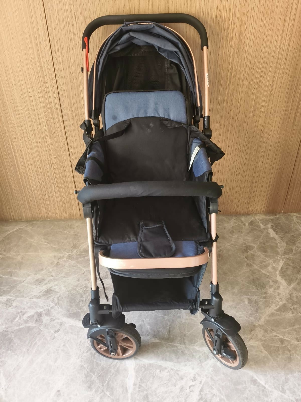Black and rose gold stroller on a stone floor