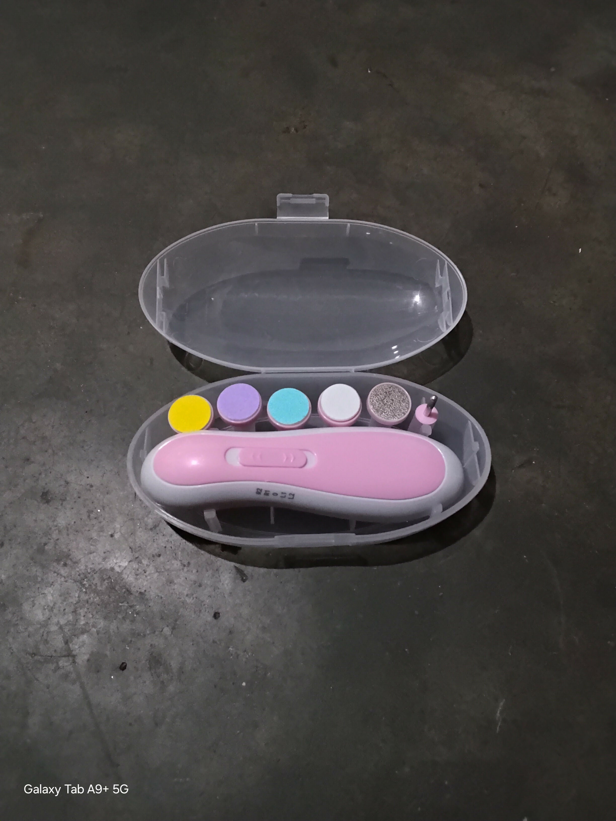 Pink nail art tool set with colorful dots in a clear case on a dark surface
