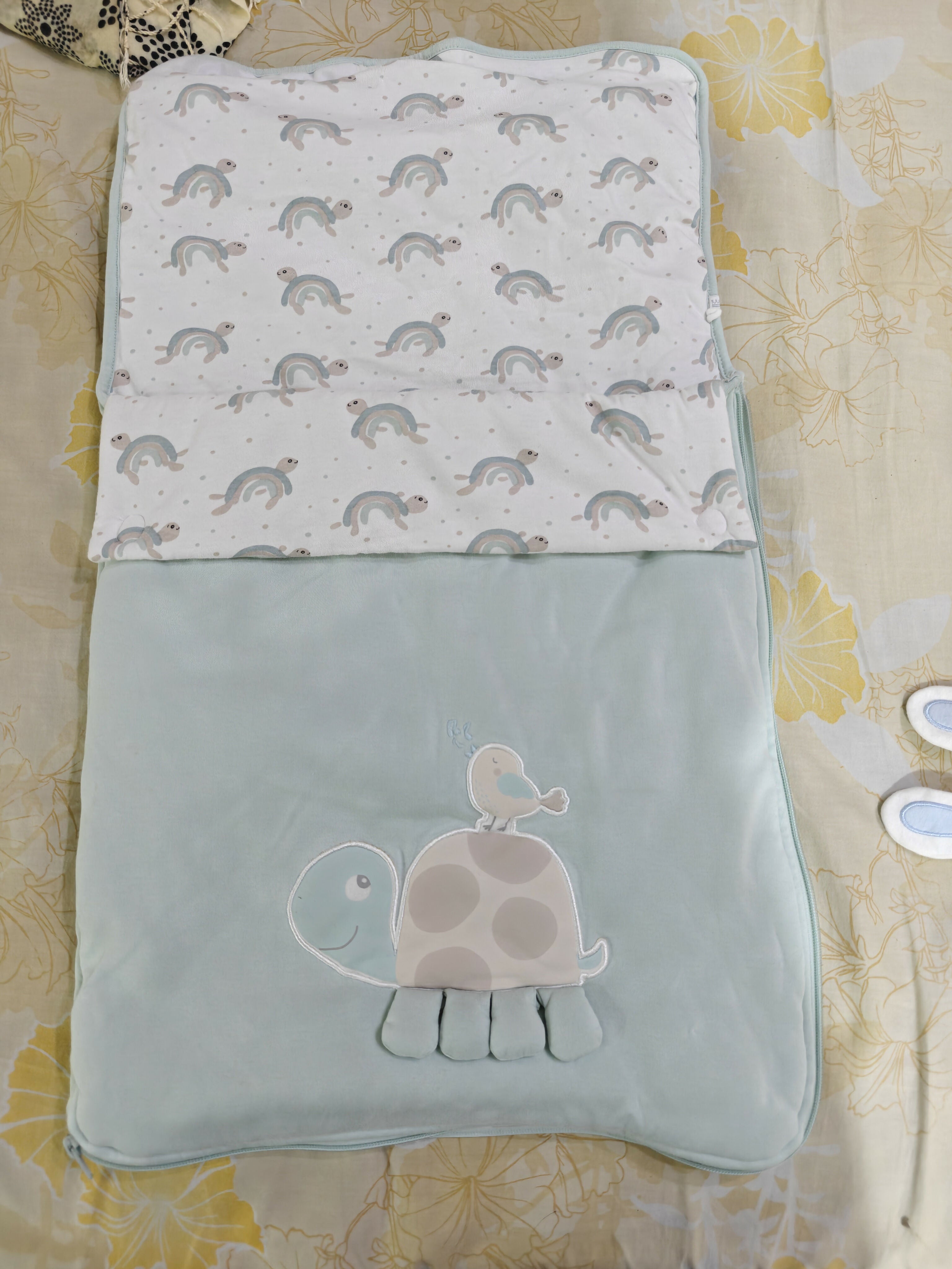 Baby blanket with turtle pattern on a yellow floral fabric background
