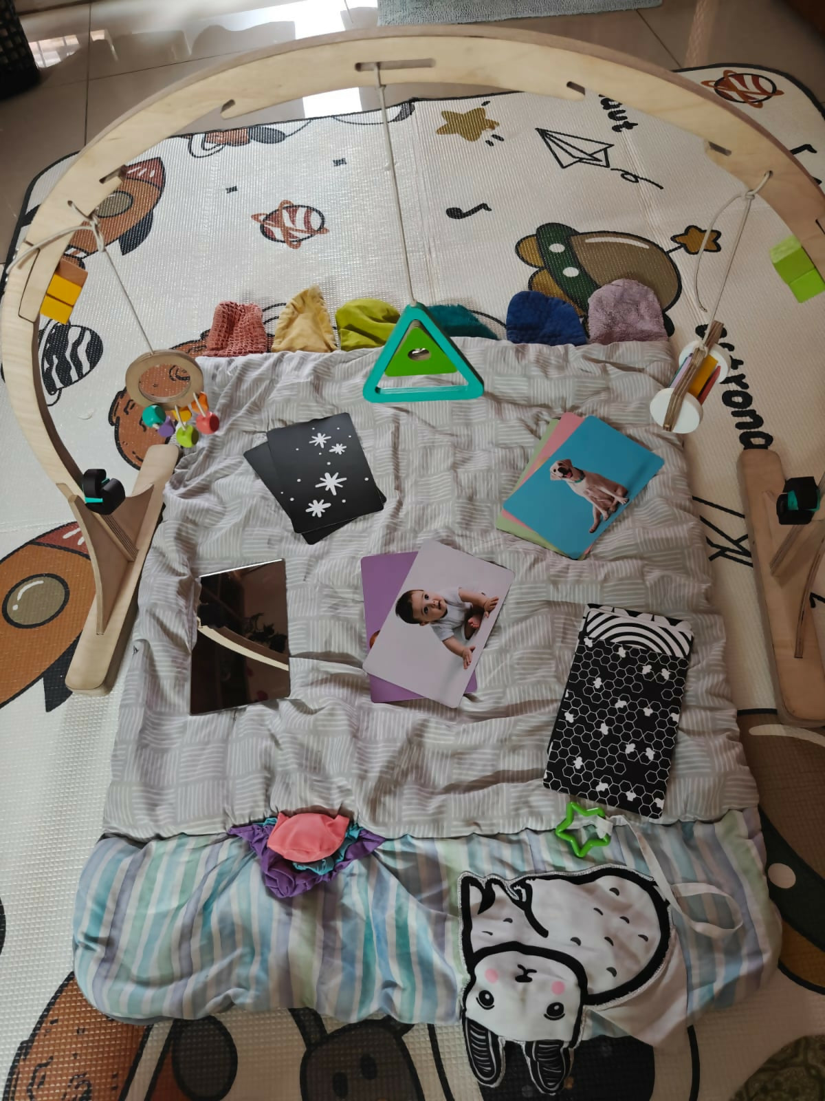 Play mat with various items including cards and toys on a wooden floor.
