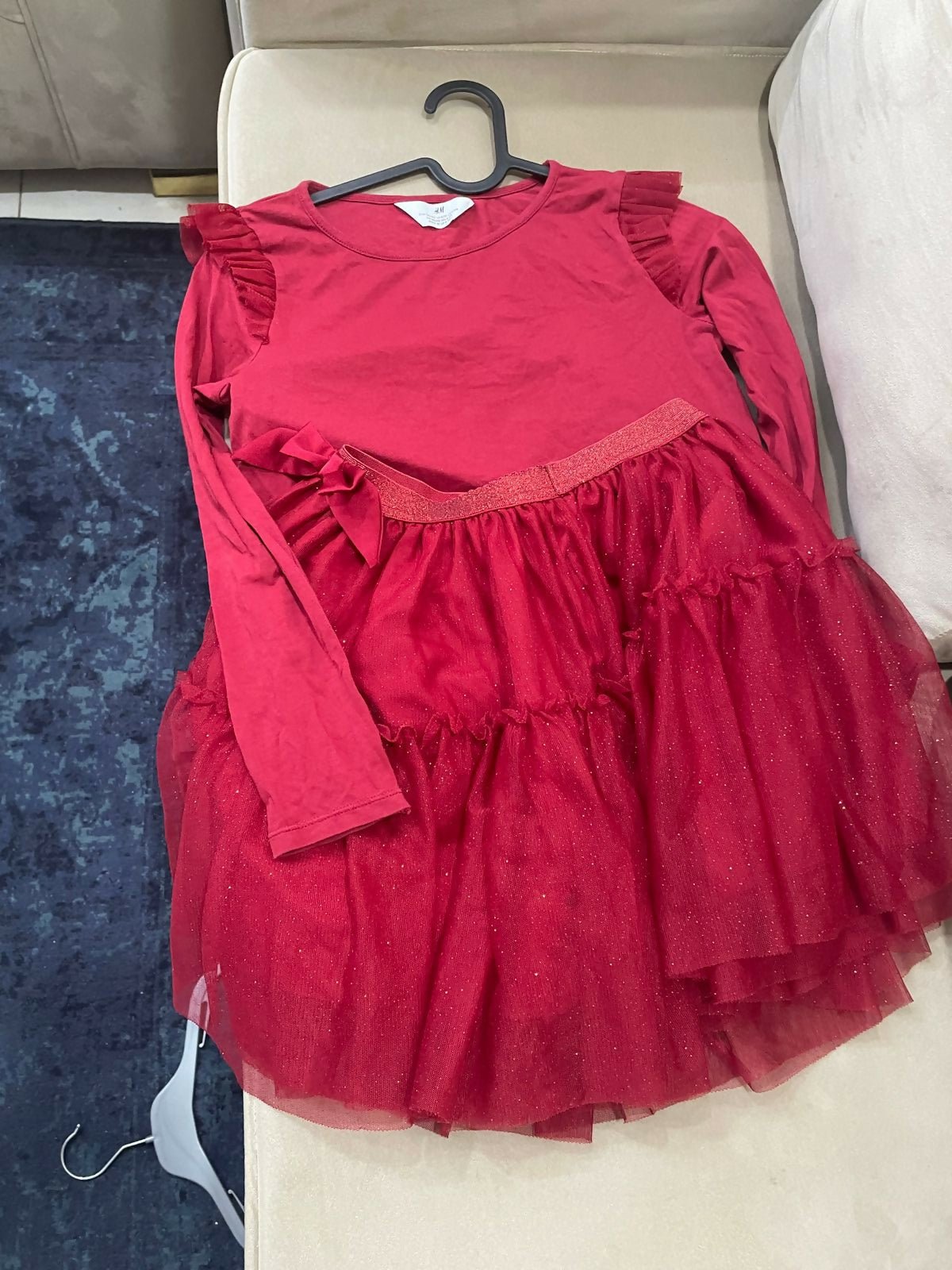 Red dress with ruffled layers on a hanger against a neutral background