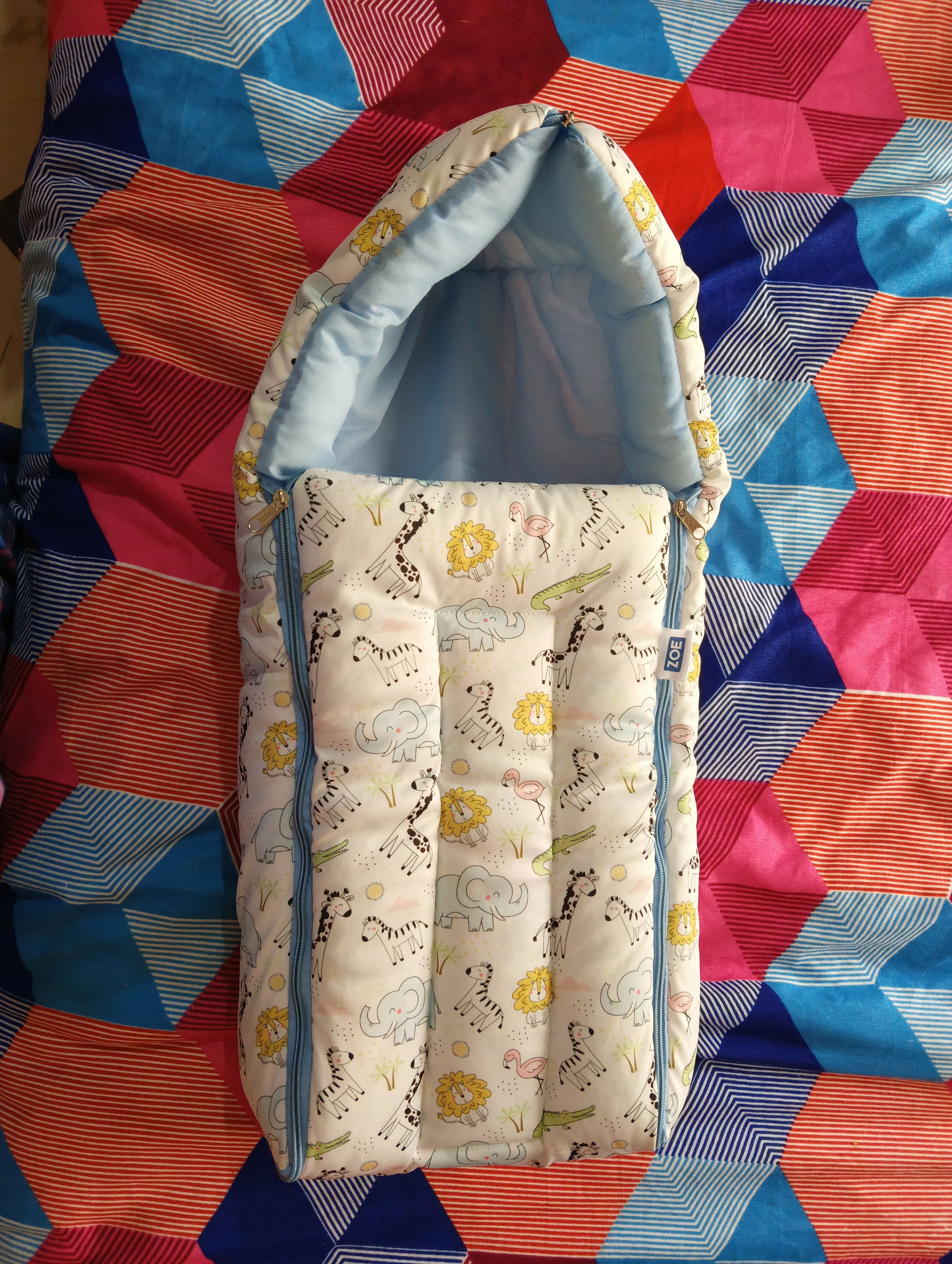 Baby crib with patterned mattress on a colorful quilt