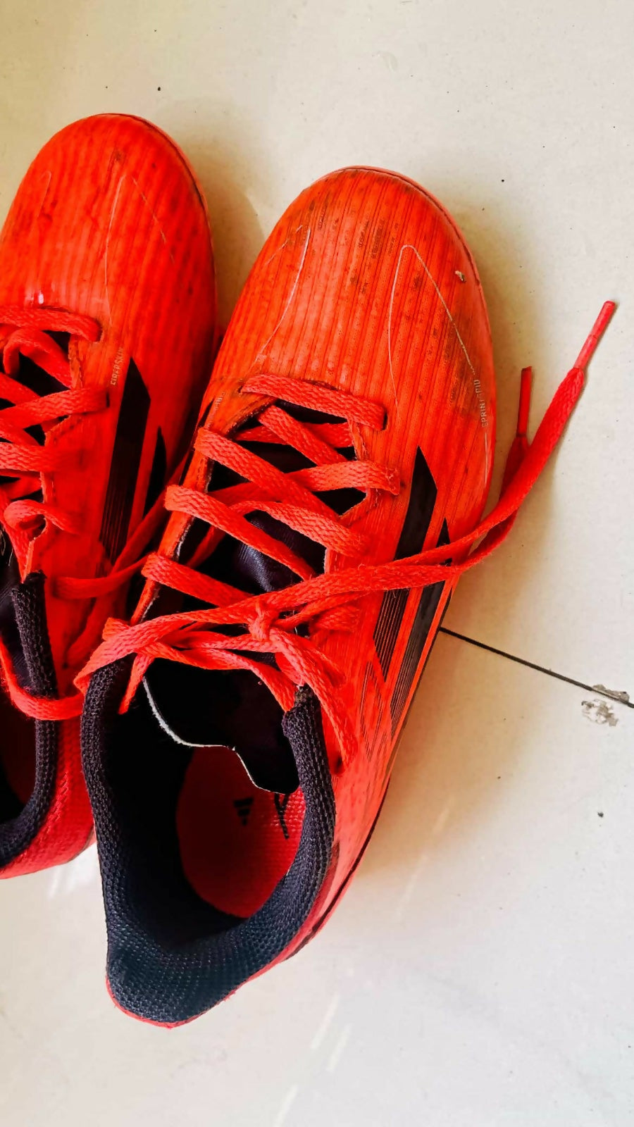 Red athletic shoes with black soles on a white surface