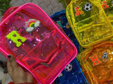Colorful transparent bags with decorative charms and letters on a blurred background