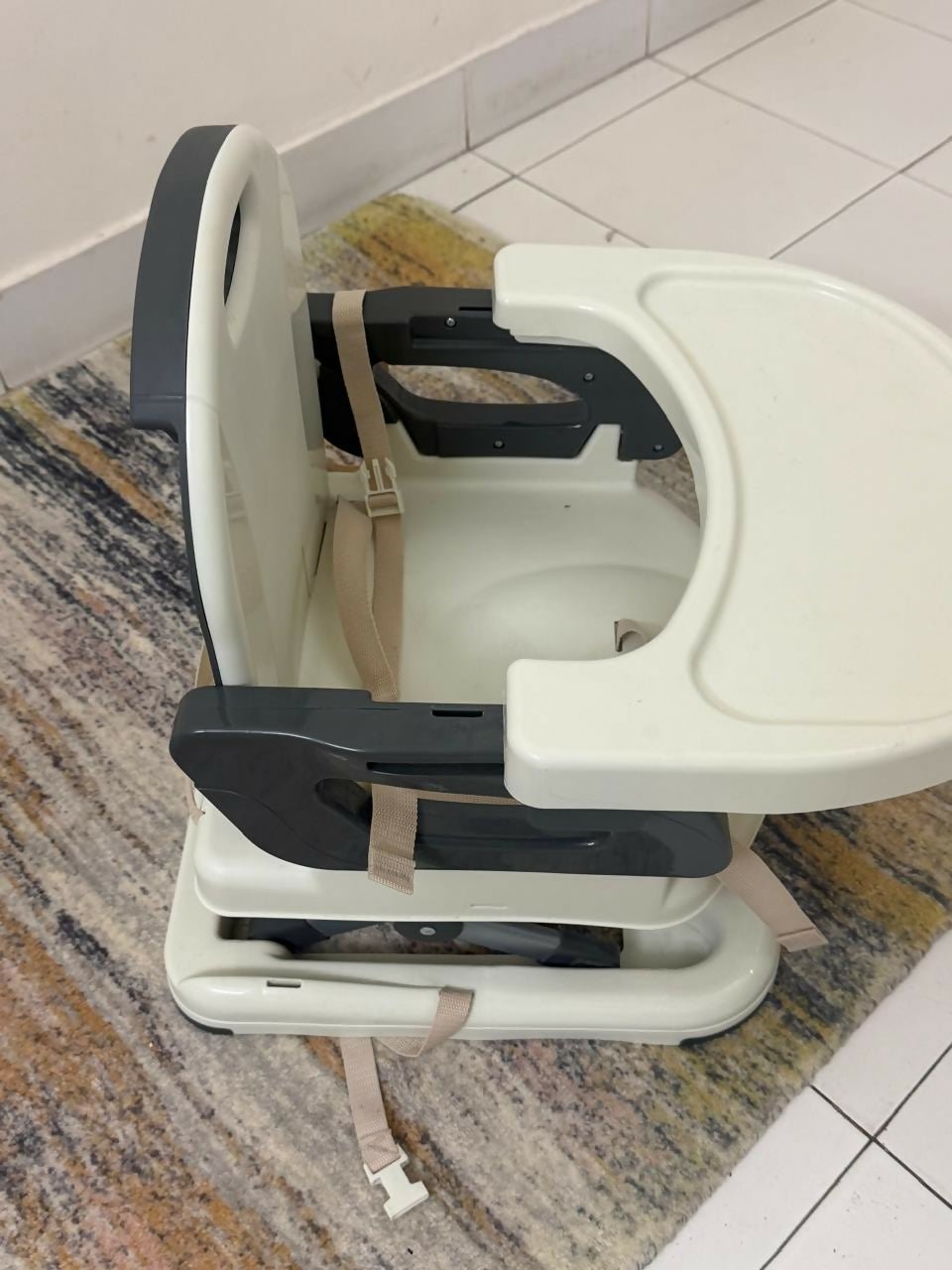 Baby high chair on a tiled floor with a rug underneath