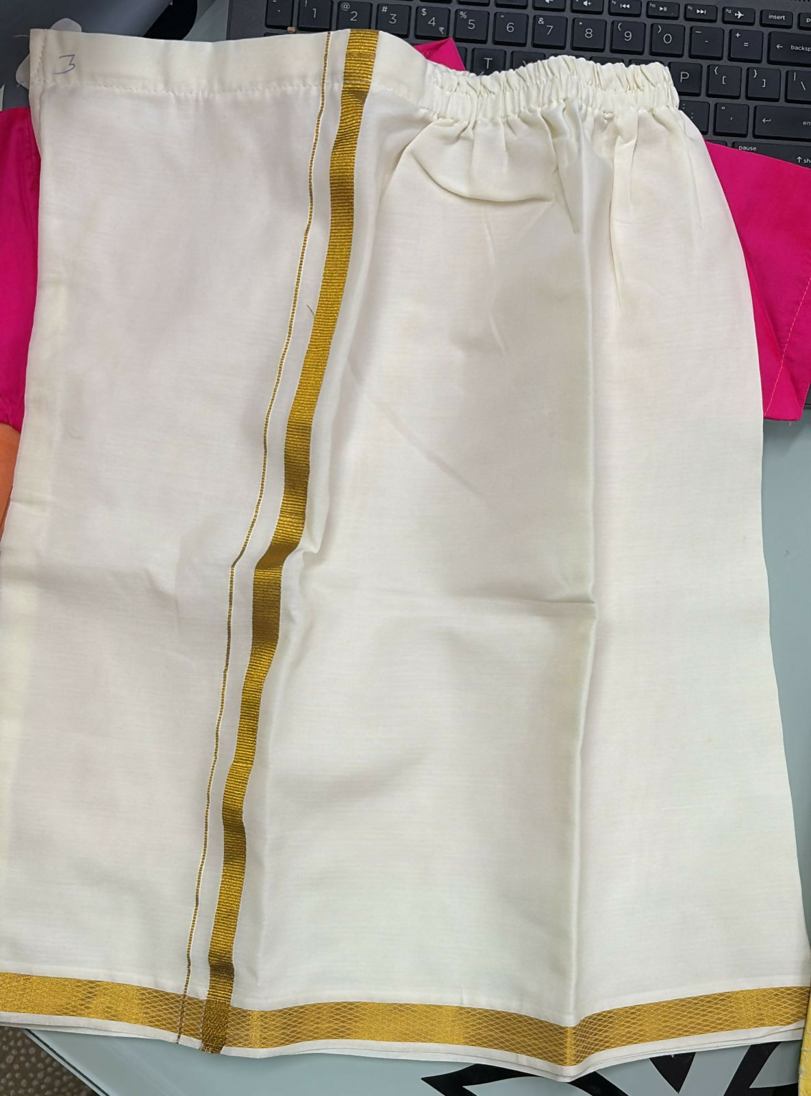 White pants with gold stripes on a pink surface
