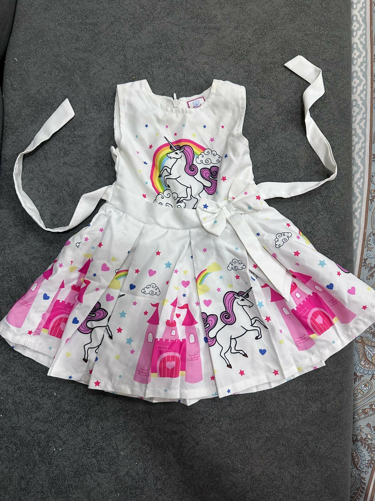 Children's dress with unicorn and rainbow designs on a dark surface