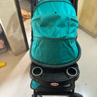 Turquoise stroller with cup holders on a tiled floor