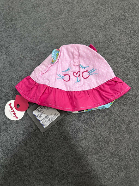 Pink baby hat with ruffled edge on a gray surface