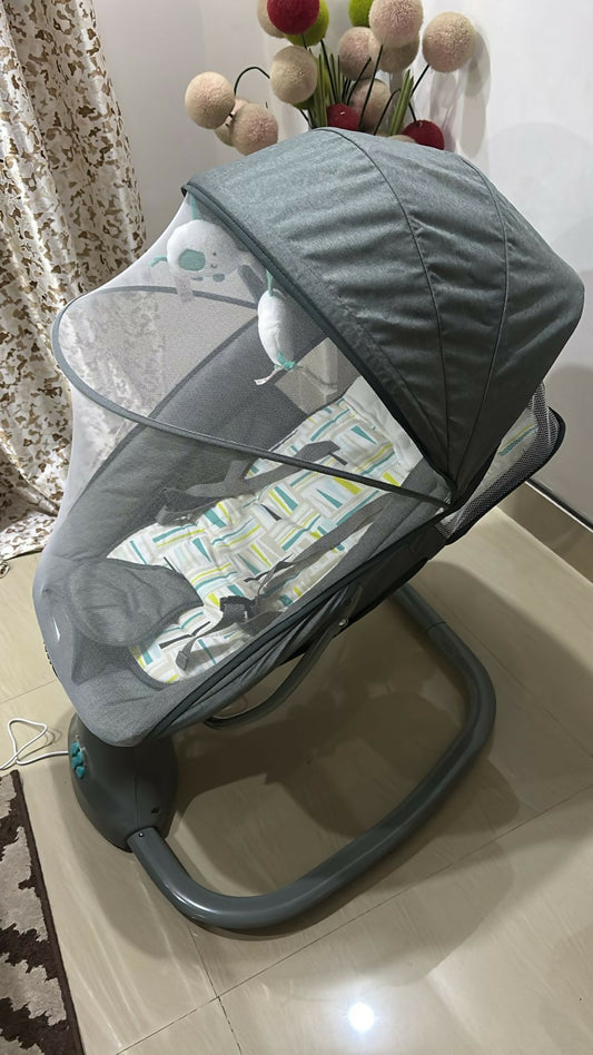 Gray baby swing with canopy on a light-colored floor.