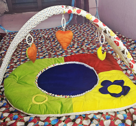 Colorful baby play mat with various toys on a patterned floor.