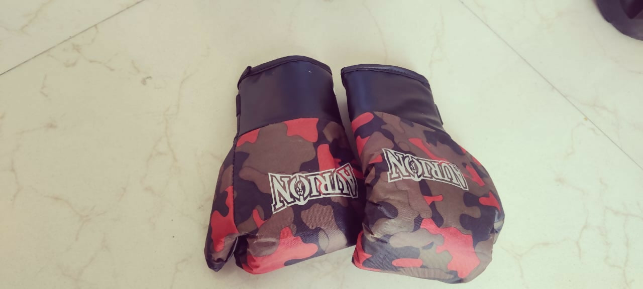 Camouflage-patterned boxing gloves with 'Nomix' branding on a light-colored floor.