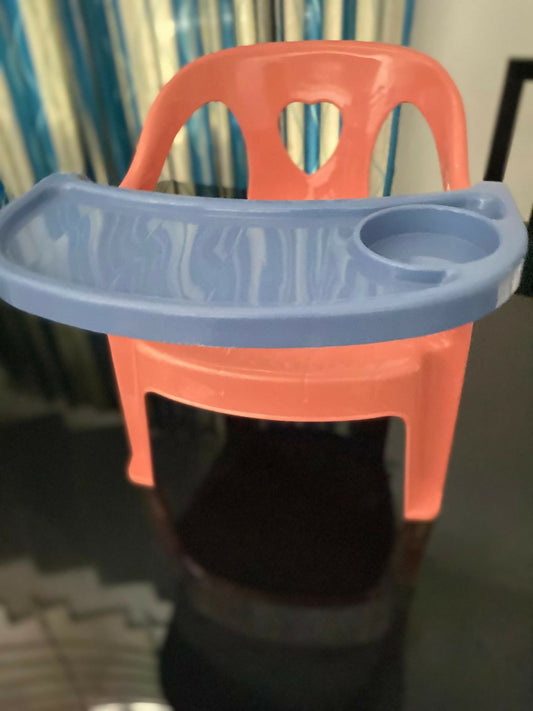 Red plastic chair with a blue tray on a dark background