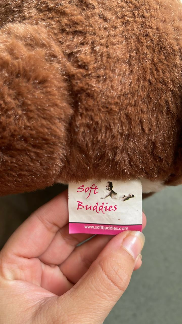 Hand holding a brown plush toy with a 'Soft Buddies' label.