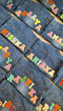 Denim jackets with colorful text labels on a flat surface