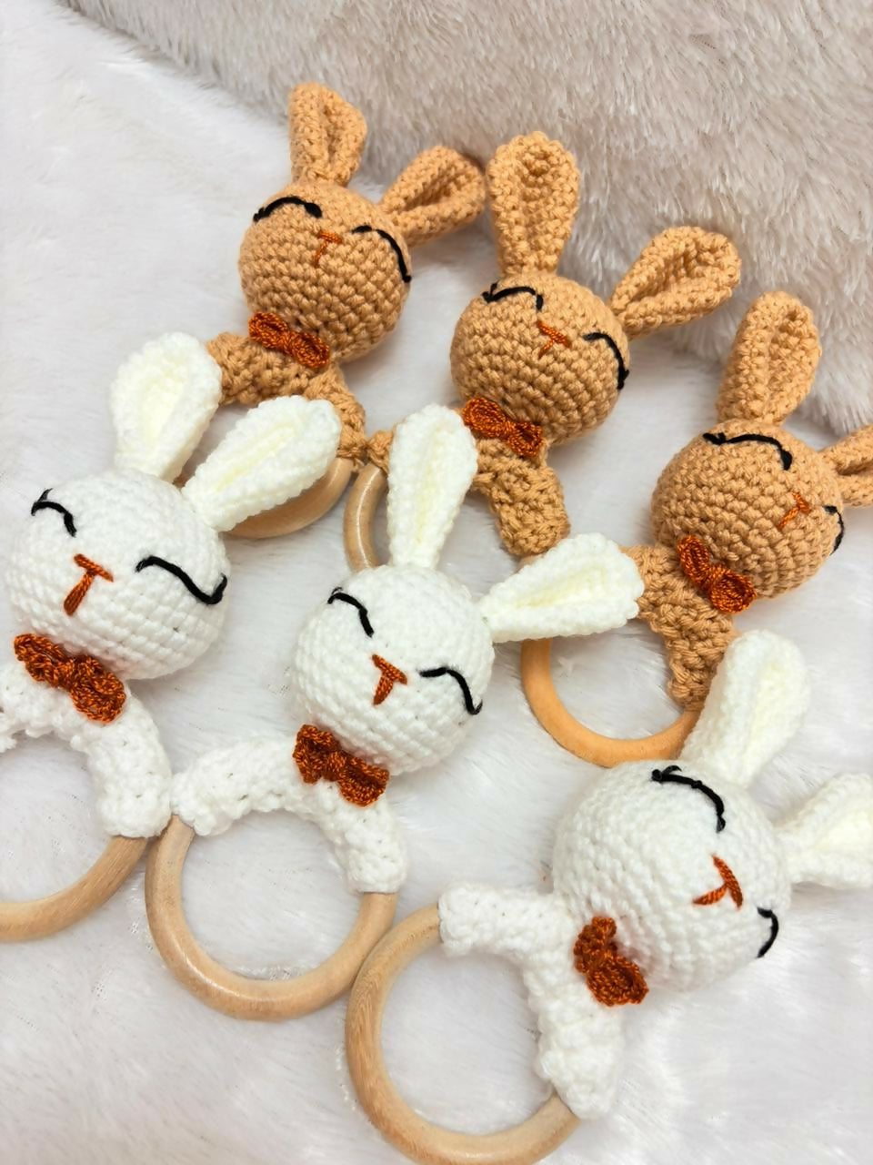 Set of crocheted bunny rattle toys on a soft surface