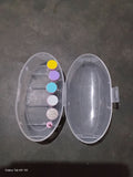 Clear plastic container with colorful buttons on a dark surface