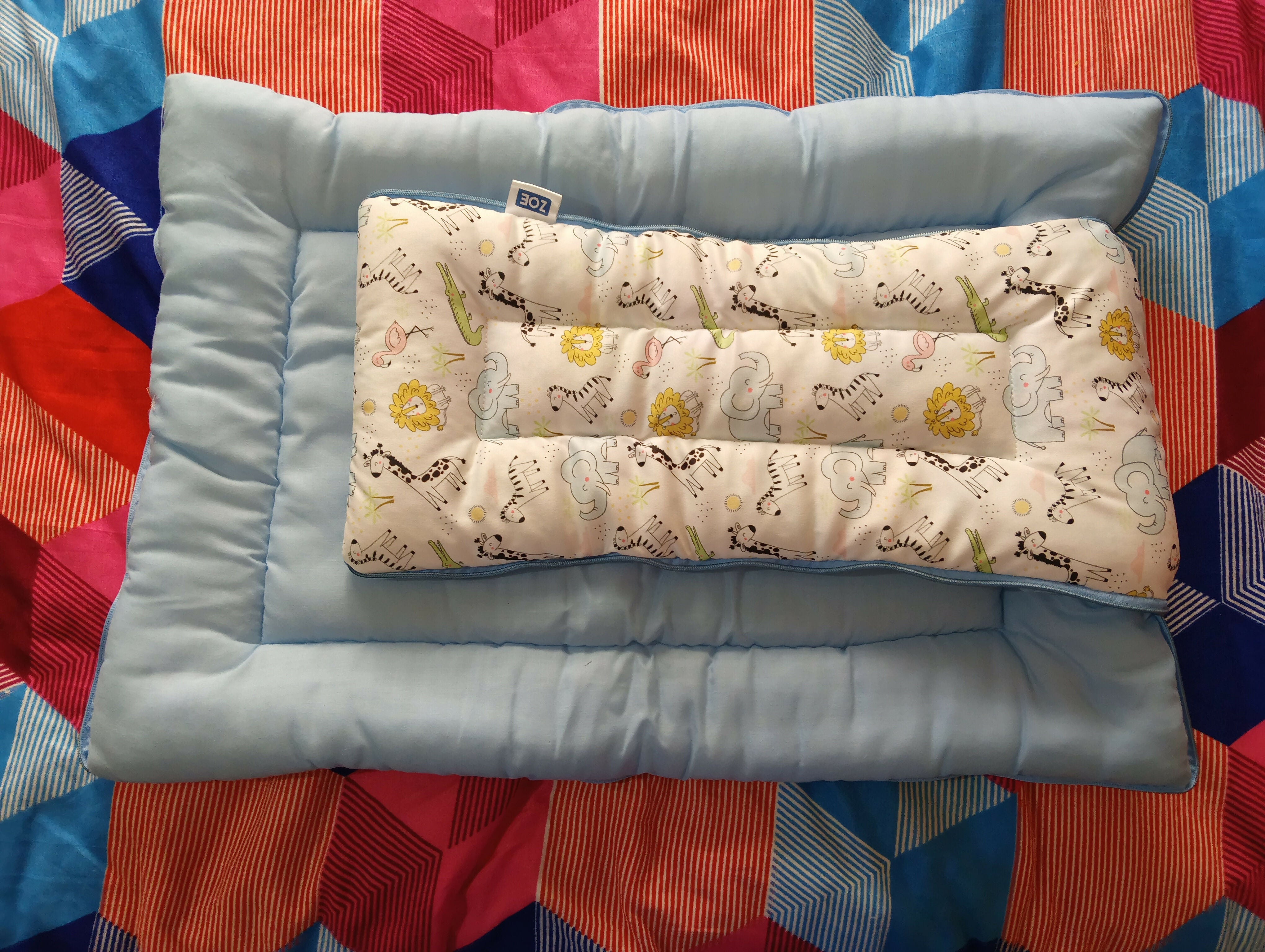 Baby crib bumper with patterned insert on a colorful quilt