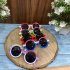 Colorful children's sunglasses on a wooden board with flowers in the background