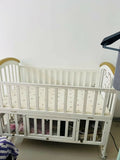 Shop Huny Huny Convertible Baby Cot – Wooden crib with storage, teething rails, wheels, and adjustable height.