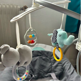 Baby crib mobile with plush toys and hanging rings on a crib
