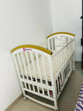 Shop Huny Huny Convertible Baby Cot – Wooden crib with storage, teething rails, wheels, and adjustable height.