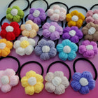 Colorful knitted flower hair ties on a pink background