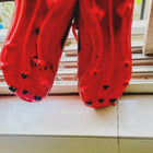 Red sandals with black heart patterns on a light-colored floor.