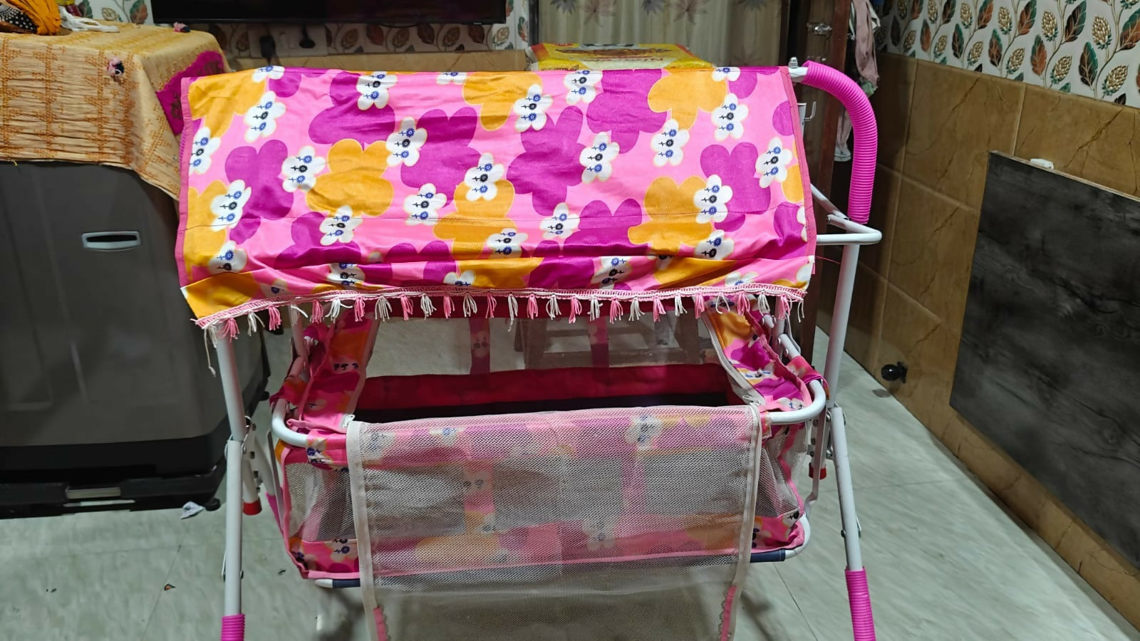 Children's toy cart with colorful floral and polka dot fabric cover in a room setting.
