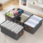 Gray storage boxes with handles containing folded clothes and toys on a bed.