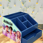Blue desk organizer with a personalized design on a wooden surface with decorative elements.