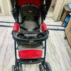Red and black stroller with 'Cortina' branding on a marble floor.