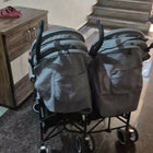 Two gray bags on wheels in a room with a staircase and wooden desk.