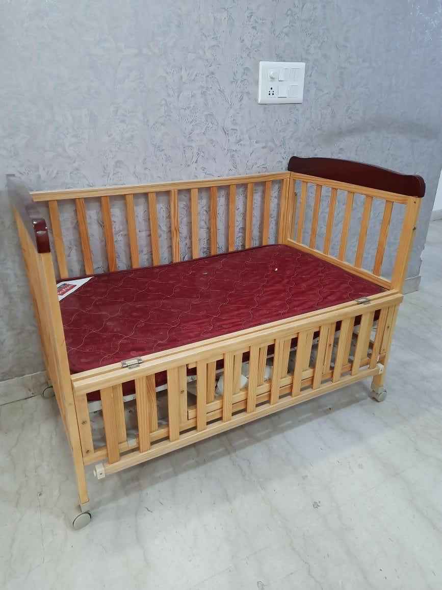 Wooden crib with red mattress 