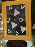 Small black board with white triangle shapes on a yellow frame