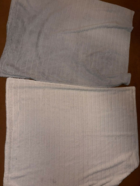 Two folded towels, one gray and one white, on a wooden surface.
