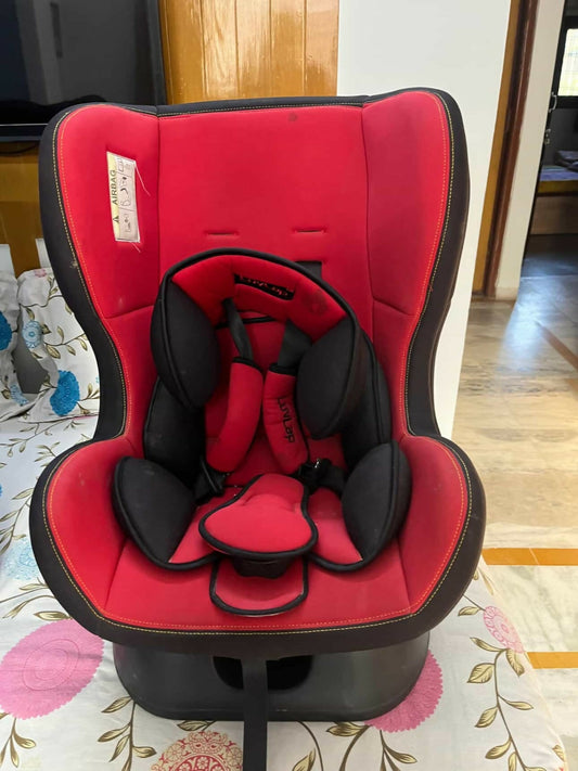 Red and black baby car seat on a floral-patterned rug