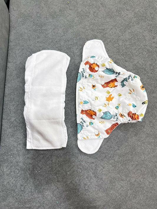 Two baby diapers on a gray surface, one plain and one with colorful designs.
