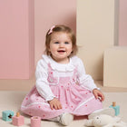 Child wearing a pink checkered dress with white shirt