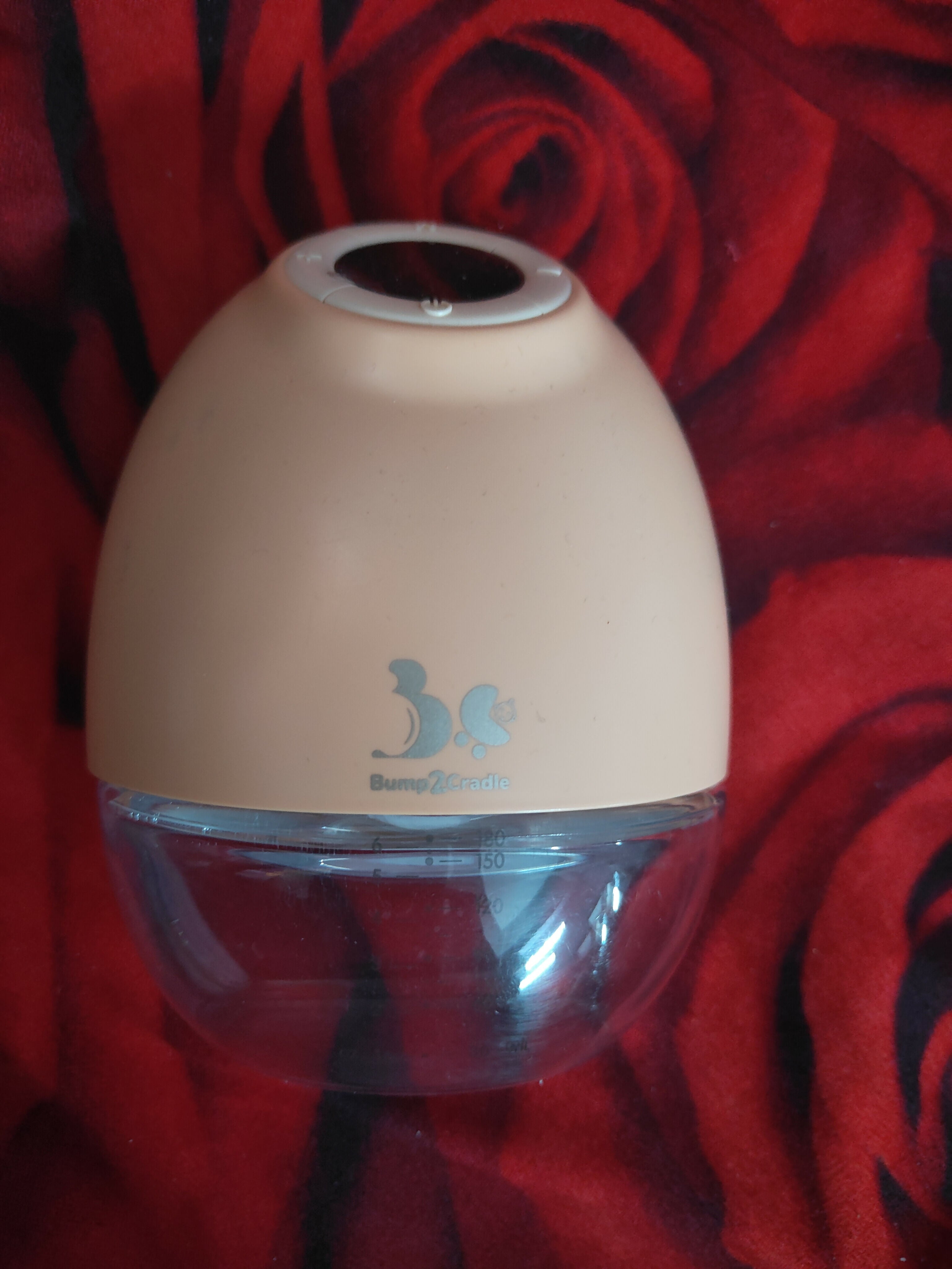 Beige humidifier with a clear water tank on a red floral background