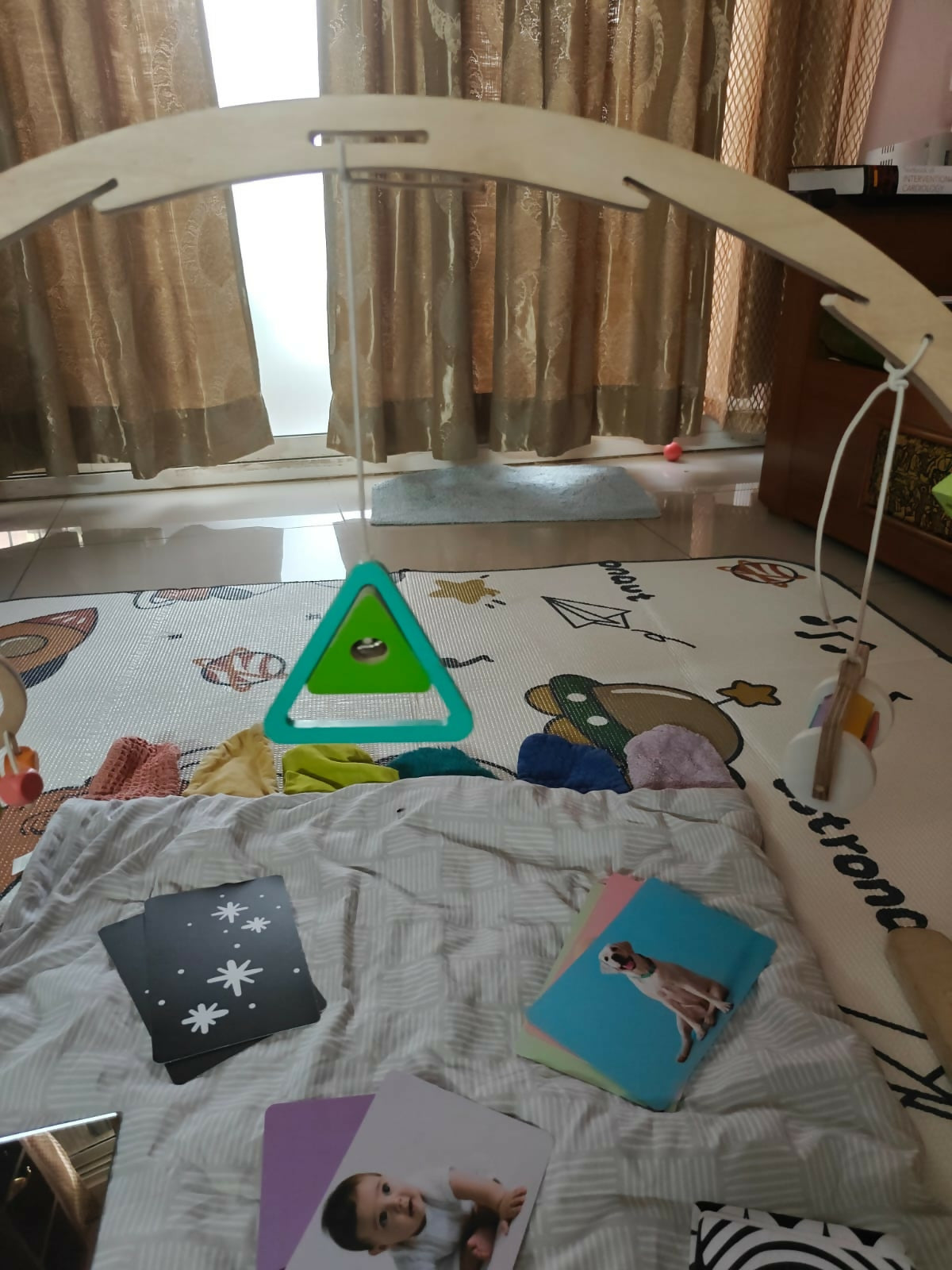 Baby play area with a wooden arch, colorful mat, and educational toys.