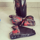 Camouflage-patterned boxing gloves and punching bag on a tiled floor.