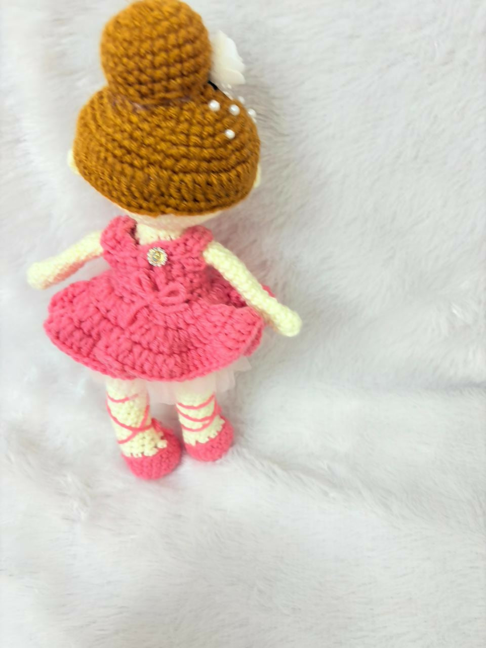 Crocheted doll with a pink dress and brown hat on a white background