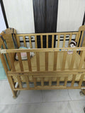 Wooden crib with wheels on a tiled floor against a striped wall.