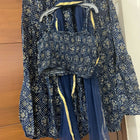 Blue floral-patterned outfit with a top and skirt on a hanger against a wooden background
