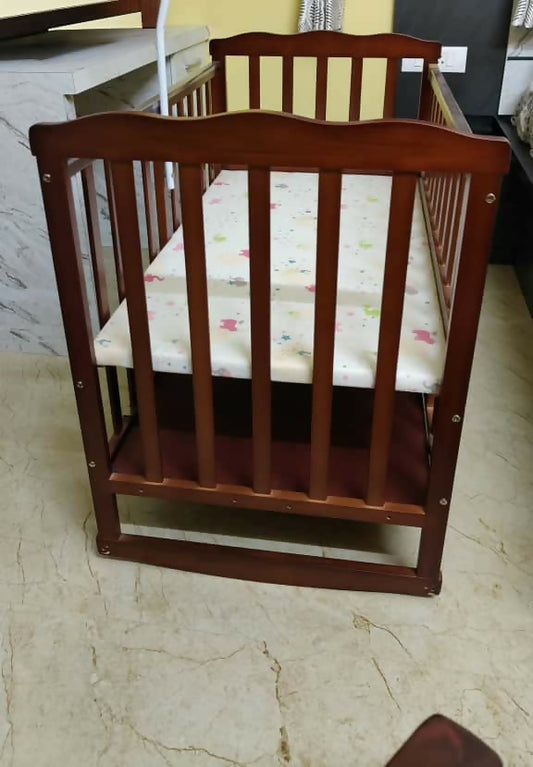 Wooden crib with a white mattress on a marble floor