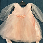 Pink dress with sheer sleeves on a hanger against a blue textured background